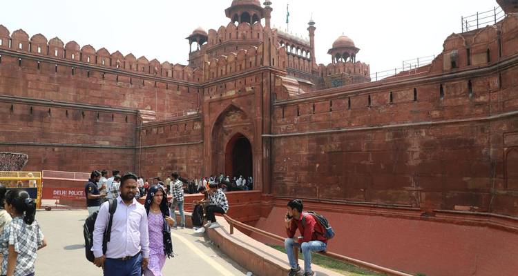 People walking alongside a large historic fort entrance.