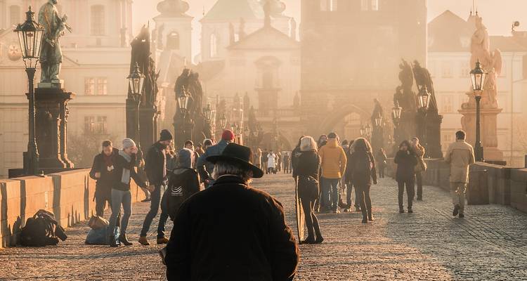 People walking on Charles Bridge in the morning mist.