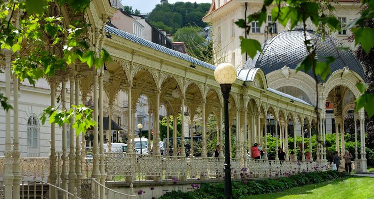 Ornate walkway and pavilion in Karlovy Vary surrounded by greenery.