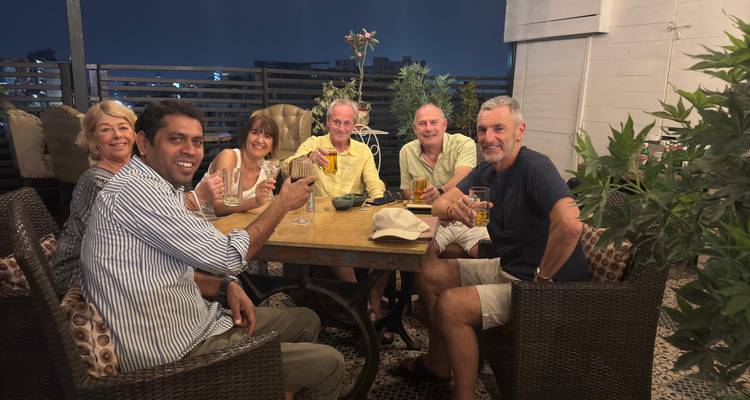 Un groupe de personnes savourant des boissons sur une terrasse sur le toit la nuit.