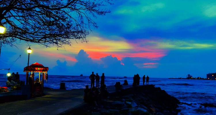 Een levendige zonsondergang boven de oceaan met mensen als silhouet op de voorgrond.