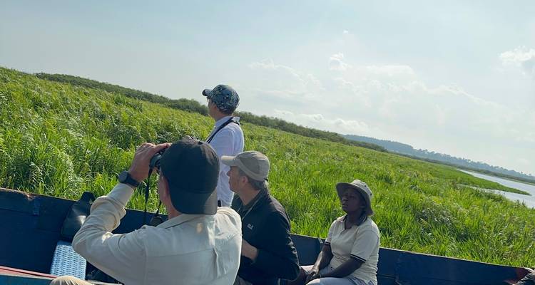 Tourists on a safari boat looking at marshland.