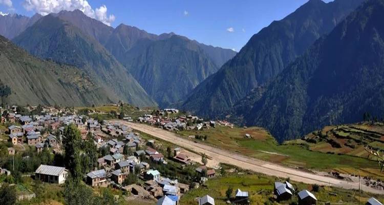 Vue panoramique d'une vallée avec un petit village et une végétation luxuriante.