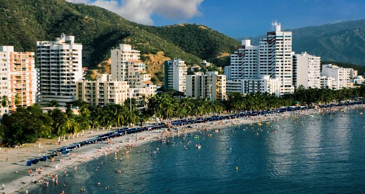 High-rise beachfront skyline of Santa Marta with packed beach and blue mountains beyond