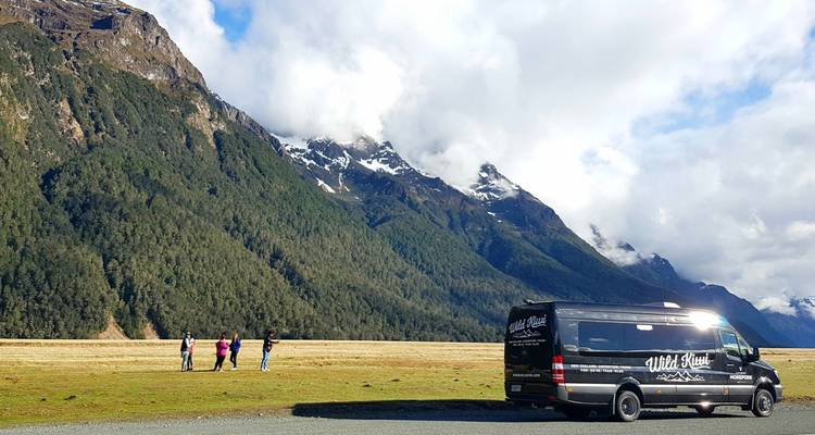 Autocar de tourisme garé dans un vaste paysage avec des montagnes.