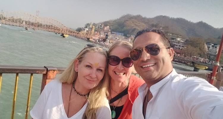 Three people posing for a selfie with a river and bridge in the background.