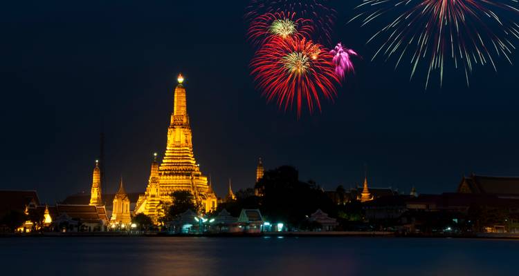 Wat Arun Tempel nachts beleuchtet mit Feuerwerk am Himmel.