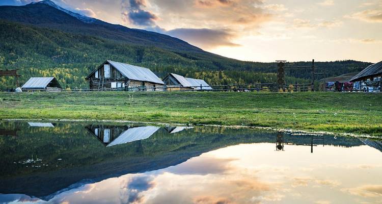 Reflection of clouds and countryside buildings on a calm lake.
