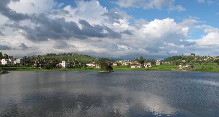 Lac entouré de petites agglomérations et ciel nuageux.