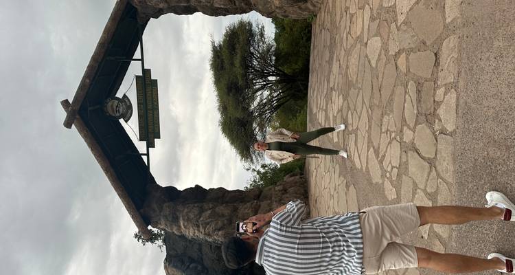 Person posing under the entrance arch of a national park.