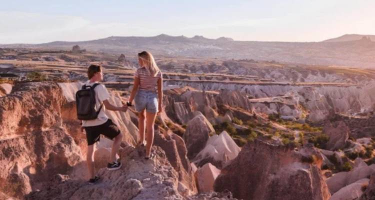 Couple standing on rocky landscape enjoying a vast view.
