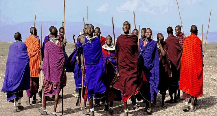 Un groupe de personnes en tenues traditionnelles colorées debout sur un terrain découvert.