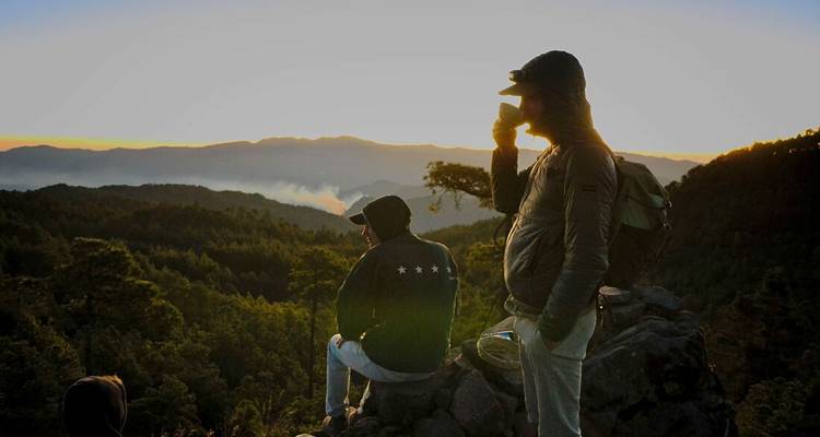 Two people enjoying a sunrise in a mountainous area.