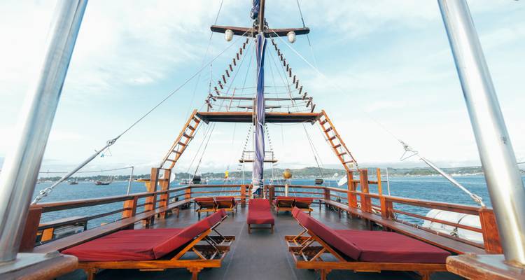 Pont d'un bateau avec des chaises longues rouges et une vue sur la mer.
