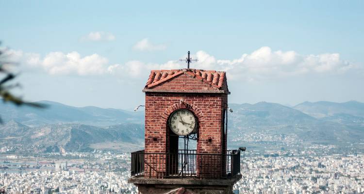 Clock tower with view of the cityscape and mountains in the background.