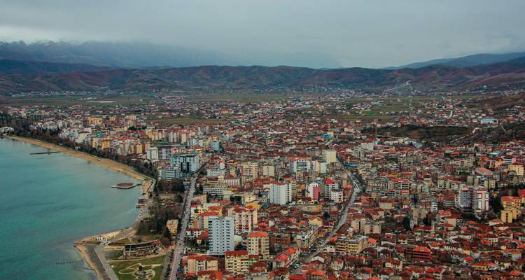 Aerial view of a sprawling city surrounded by mountains and a lake.
