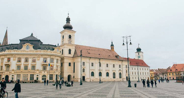 Historic square with baroque architecture and people walking.