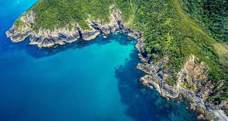 Aerial view of a stunning, rocky coastline with vibrant blue waters.