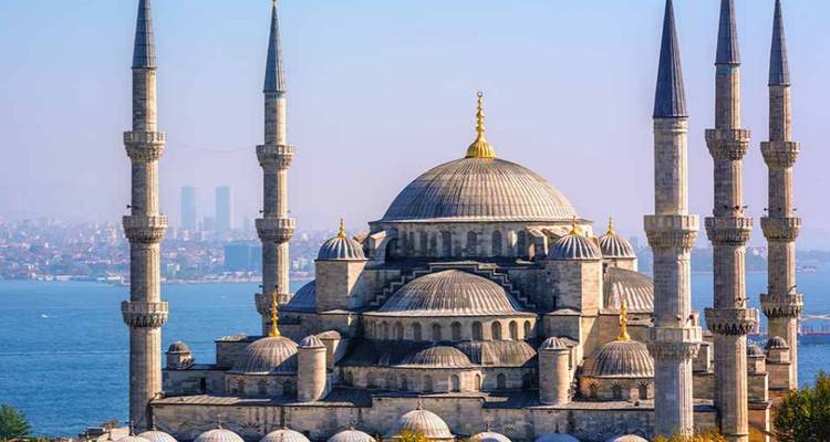 Iconic mosque with prominent domes and minarets by the sea.