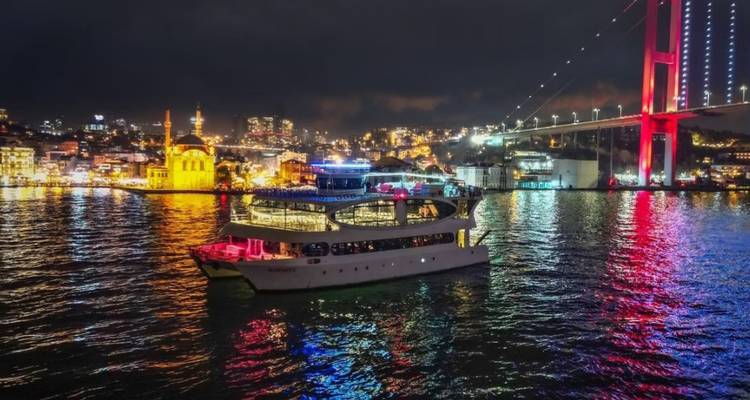 Boat sailing in a city harbor at night with illuminated buildings.