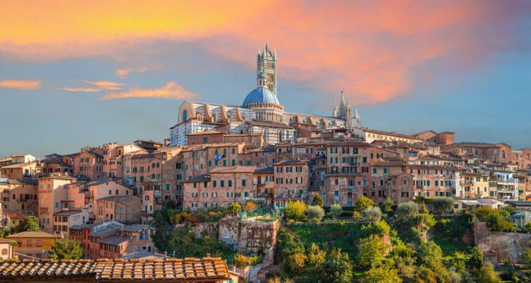 View of a historic town with a cathedral at sunset.
