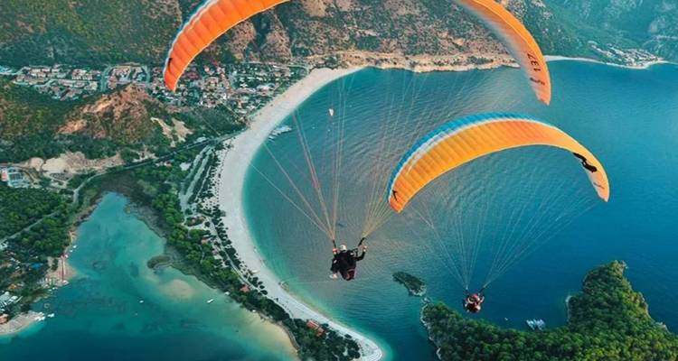Paraglider über einem Strand und blauem Wasser.
