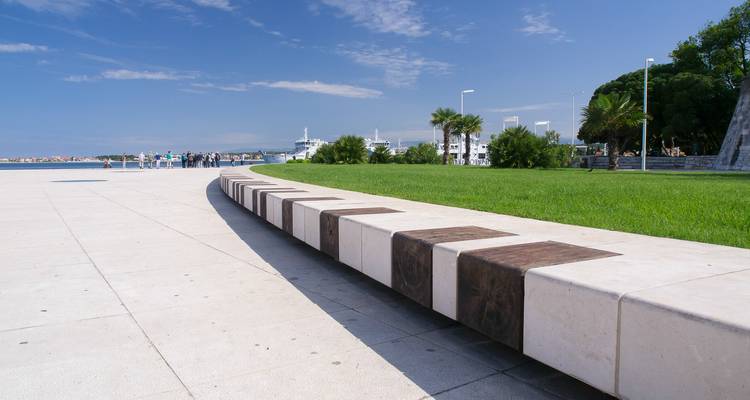 Coastal park with a promenade and palm trees.