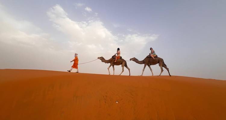 Deux personnes à dos de chameaux dans le désert.