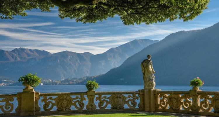 Une vue panoramique au bord du lac avec des montagnes en arrière-plan, encadrée par une statue.
