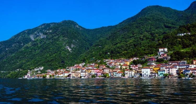 Ville pittoresque à flanc de colline avec des maisons colorées le long d'un lac tranquille.