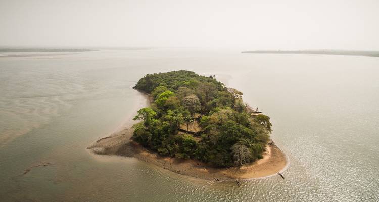Une petite île boisée entourée d'eau sous un ciel brumeux.