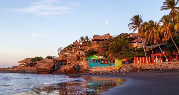 Cabanes de plage colorées et eau calme pendant le coucher de soleil.