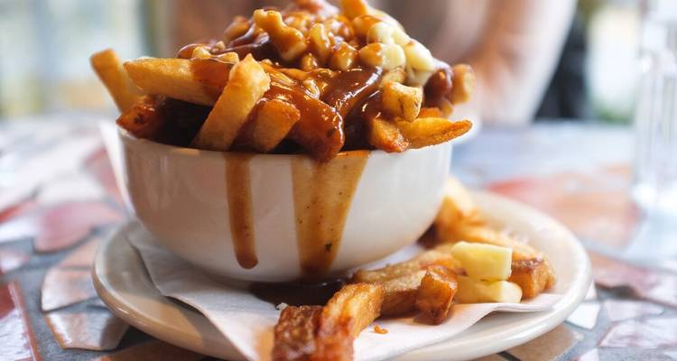 Bol de poutine avec garnitures qui débordent.