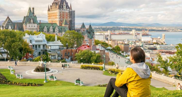 Personne assise sur une colline avec vue sur la ville de Québec et le Château Frontenac.