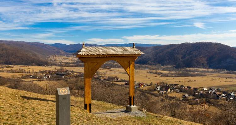 Wooden gate with a scenic view of a valley and mountains.