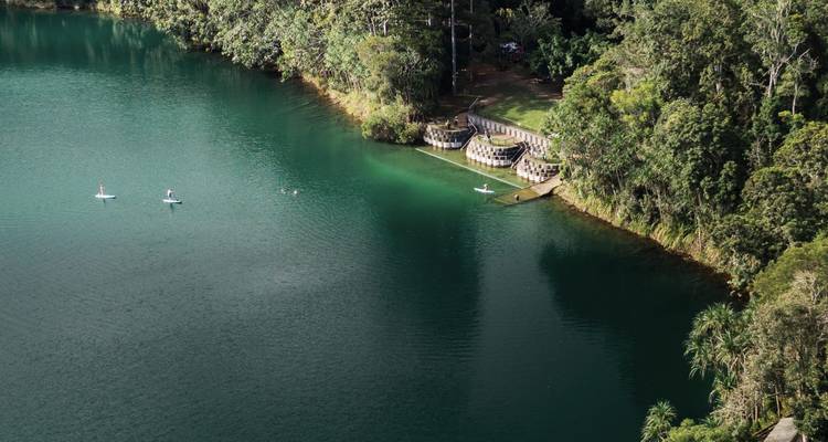 Lac vert émeraude calme entouré d'une forêt dense avec des gens qui pagaient.