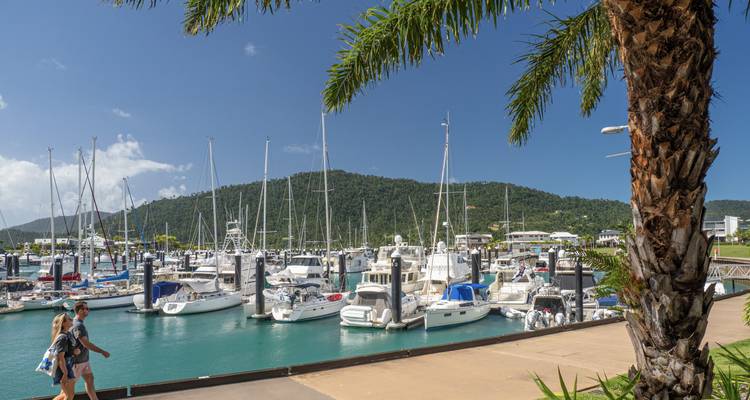 Marina avec des bateaux amarrés et des gens qui se promènent le long du front de mer.