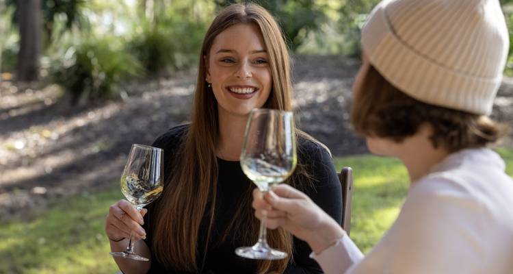 Dos personas disfrutando copas de vino al aire libre.