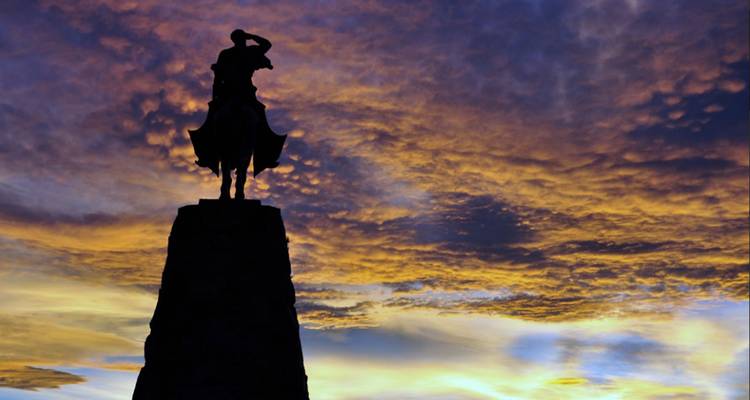 Silhouet van een standbeeld tegen een indrukwekkende kleurrijke zonsonderganghemel.