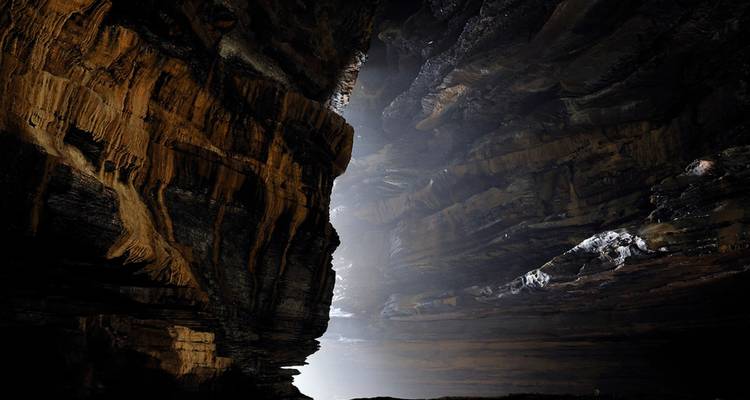 Dark and dramatic cave with light streaming through.