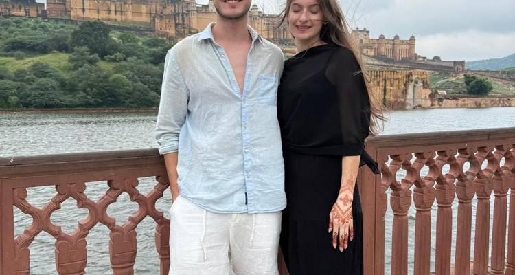 Couple près d'une rambarde au bord d'un lac avec un fort en arrière-plan.