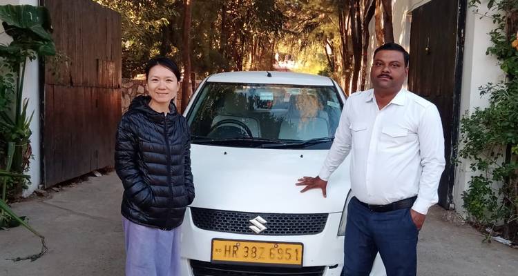 Deux personnes posant à côté d'une voiture dans une allée.