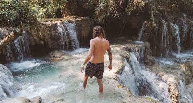 Person enjoying a natural waterfall pool
