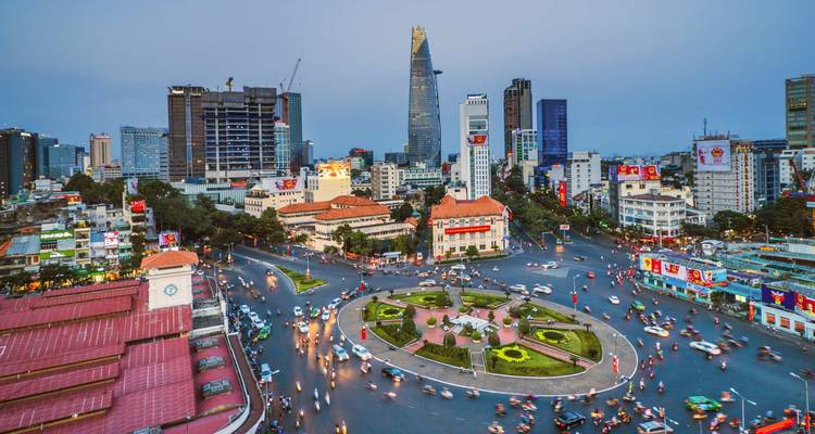 Bustling city square with tall modern buildings and busy traffic.