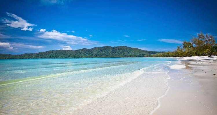 A pristine beach with clear water and blue sky.