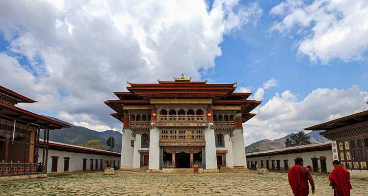 Ein bhutanischer Dzong mit Menschen, die im Innenhof spazieren gehen.
