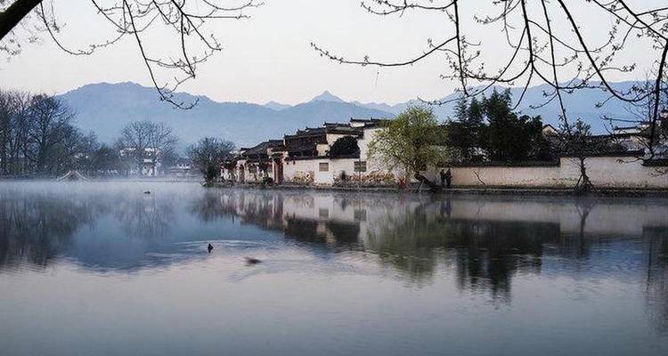 Lakeside view of a village with reflection in calm water.