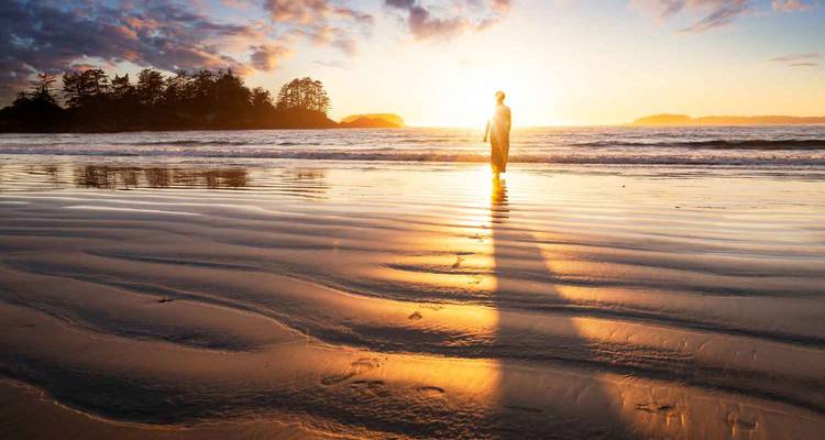Personne marchant le long d'une plage au coucher du soleil.