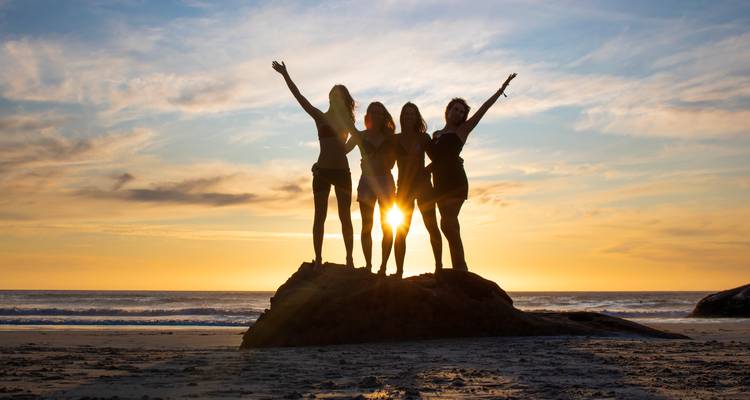 Groupe d'amis célébrant sur la plage au coucher du soleil.