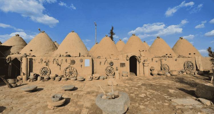 Traditional beehive-shaped mud houses under a blue sky.